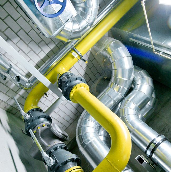 Gelbe Gasleitung zwischen gedämmten Rohrleitungen