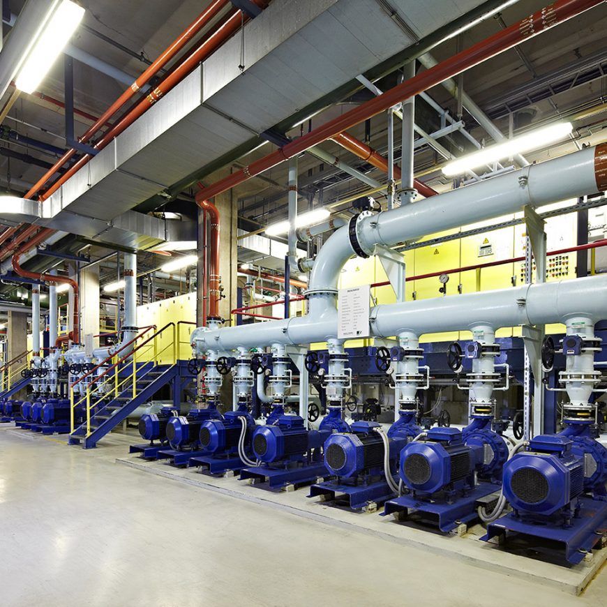 Pumpenreihe mit Rohrleitungen in einer Industriehalle