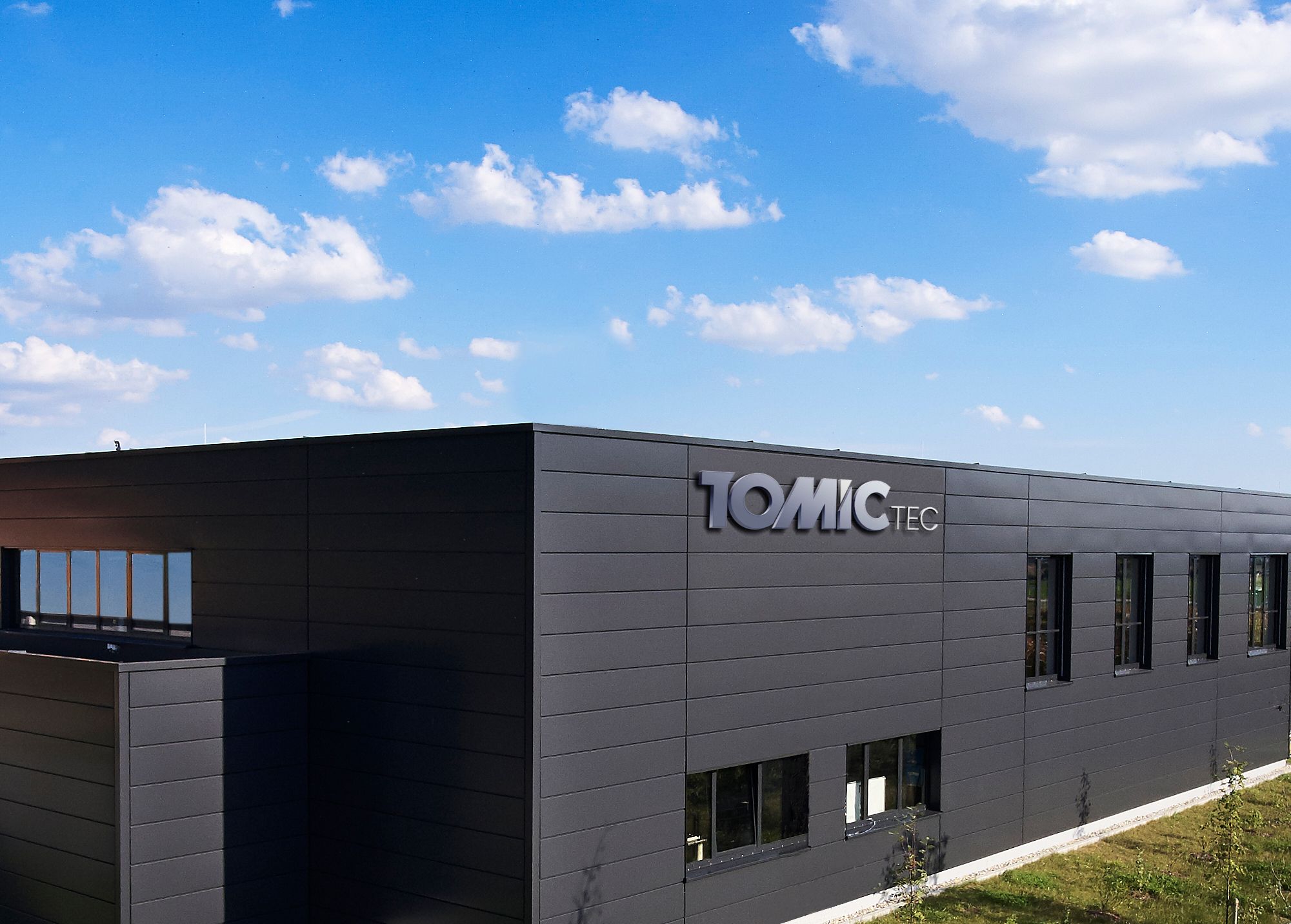Gebäude von Tomic TEC mit Logo an der dunklen Fassade
